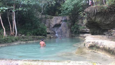 Lokale-Indonesische-Kinder-Spielen-In-Einem-Wunderschönen-Blauen-Süßwasserflussbecken-Mit-Wasserfall-Auf-Der-Insel-Java