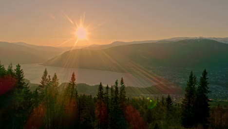 Drone-trucking-shot-of-a-setting-sun-over-the-Aurlandsfjord-with-sunflaires-in-the-lens