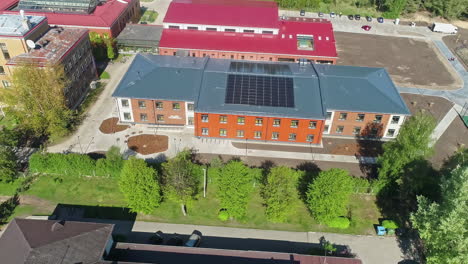 High-angle-drone-panning-shot-of-a-modern-school-in-Latvia-on-a-sunny-day