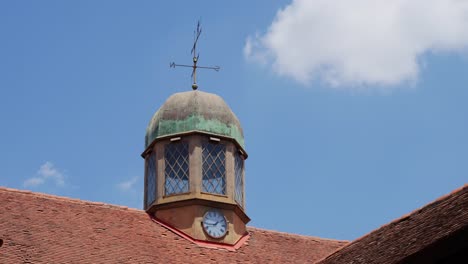 Static-Shot-Of-Old-Clock-And-Compass-Over-Cottage-Building-Roof