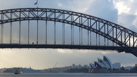 A-train-passes-over-Sydney-Harbour-Bridge-as-a-ferry-passes-below,-in-Australia