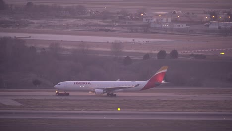 Side-view-of-Tow-truck-vehicle-pulls-Iberia-airplane-in-Madrid-airport