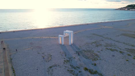 Beautiful-Light-Hits-Sculpture-on-Le-Havre-Beach-During-Sunset-Over-The-Ocean,-Wide-Angle-Drone-Establishing-Shot