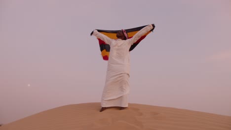 African-man-raising-flag-of-Uganda-in-the-desert
