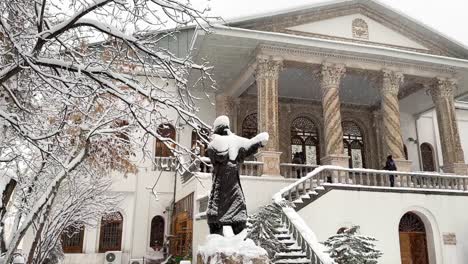 Black-statue-covered-by-heavy-snow-in-Tehran-a-Warm-white-color-traditional-historical-old-house-palace-in-city-center-with-spiral-carved-marble-stone-scenic-view-of-architectural-design-visitor-snow