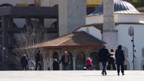 Gente-Caminando-Frente-A-La-Mezquita-En-La-Plaza-Principal-De-La-Capital-De-Tirana,-Albania