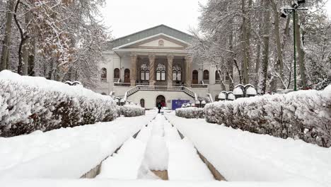 Symmetrische-Perspektive-Winter-Schneeweißes-Haus-Palast-In-Teheran-Warmweiß-Rosa-Spirale-Architekturdesign-Säule-Weitblick-Pavillon-In-Einem-Historischen-Gebäude-Im-Iran-Pool-Mit-Steinbrunnen-Alte-Bäume