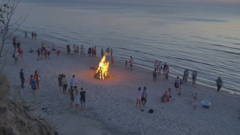 Multitudes-De-Personas-Observan-Hogueras-Encendidas-En-Una-Playa-Costera-De-Letonia-Durante-La-Puesta-De-Sol