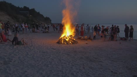 Multitudes-De-Personas-Observan-Hogueras-Encendidas-En-Una-Playa-Costera-De-Letonia-Durante-La-Puesta-De-Sol