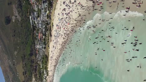 Camps-Bay-in-Cape-Town,-South-Africa-is-crowded-with-residents-an-tourists---vertical-aerial-flyover