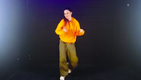 Talented-Woman-in-Baggy-Clothes-Dancing-in-Studio-with-Black-Background