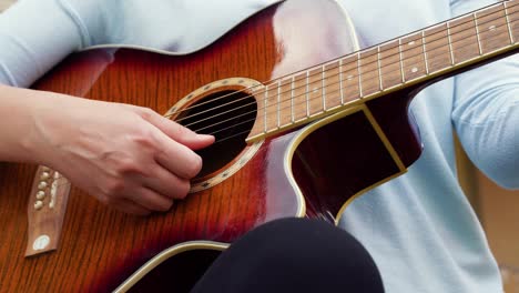 A-closeup-young-woman-plays-the-guitar-near-an-old-house