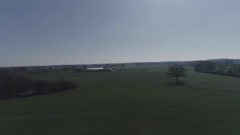 Slowly-rising-horizon-drone-shot-of-farm-town-with-agriculture-land