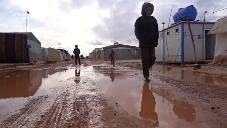 Syrian-kids-play-in-mud-outside-refugee-camp,-show-resilience-amidst-displacement