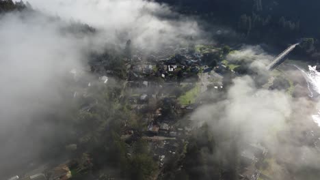 Luftaufnahme:-Kleine-Stadt-An-Einem-Fluss,-Durch-Die-Wolken-Gesehen