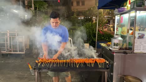 Malay-vendors-are-busy-grilling-satay-skewers-in-Jalan-Alor,-Kuala-Lumpur,-Malaysia