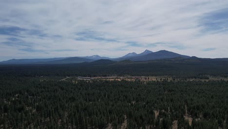 Aerial:-Flying-over-trees-in-Oregon-forest-toward-Sisters-Mountains