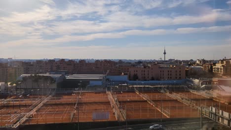 Aerial-view-of-Madrid-city-skyline-during-early-morning-with-blue-sky-and-tennis-court-as-foreground