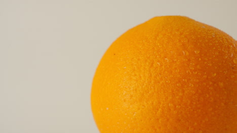 Close-up-shot-of-a-rotating-wet-orange-coverd-with-water-drops