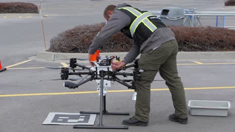 A-drone-pilot-removes-the-batteries-from-a-delivery-drone-and-places-them-into-a-bin,-slow-motion