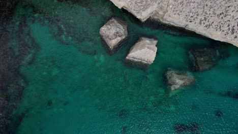 Top-Down-View-Of-Il-Kalanka-Beach-In-Malta-With-Turquoise-Water,-Splashing-On-The-Limestone-Wall