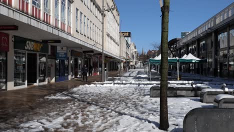 A-snowy,-sunny-pedestrian-highstreet-as-people-browse-the-shops-on-a-beautiful-sunny-day