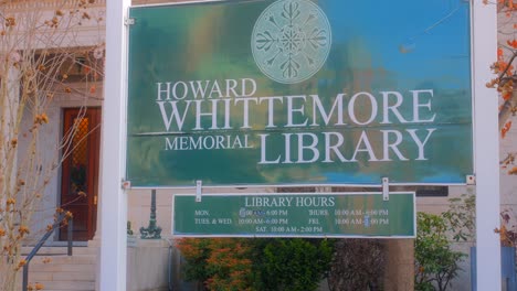 Cartel-De-La-Biblioteca-Conmemorativa-De-Howard-Whittemore-Y-Horario-De-La-Biblioteca-En-La-Entrada-En-Naugatuck,-Connecticut,-Ee.uu.