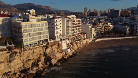 Waterfront-properties-along-the-cliffs-of-the-popular-tourist-town-of-Benidorm,-Spain---aerial