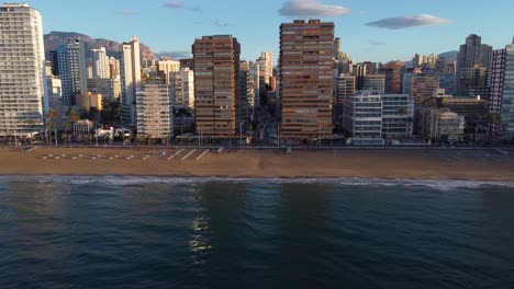 Aerial-side-view-of-several-old-apartment-buildings-on-the-beachfront-of-Benidorm,-Alicante,-Spain