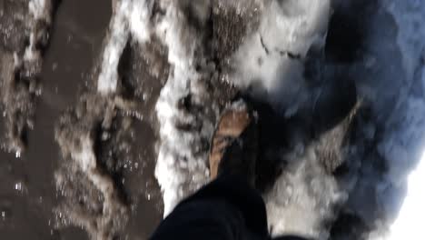 Boot-feet-walking-through-dirty-snow-and-slush-on-a-city-street