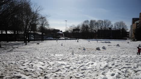Adults-and-children-in-snowy-city-park-on-sunny-day,-wide-angle,-Sheffield