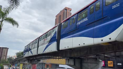 Rapid-KL-Monorail-leaving-Bukit-Bintang-station-against-the-background-of-Berjaya-Times-Square-in-Kuala-Lumpur,-Malaysia