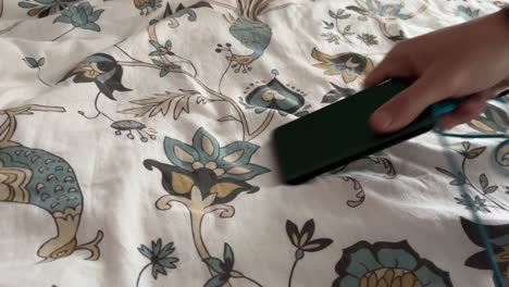 A-power-bank-with-a-cable-is-placed-on-a-bedspread-with-a-flower-and-taken-away-again