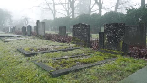 Misty-atmosphere-at-graveyard,-camera-moves-along-the-grave-stones,-time-passing-grieving-and-sadness-concept
