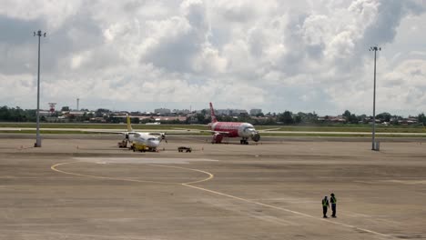 Passenger-Airplanes-Parked-On-The-Tarmac-Of-An-Airport-With-Ground-Crews-Standing-In-Foreground-In-Cebu,-Philippines