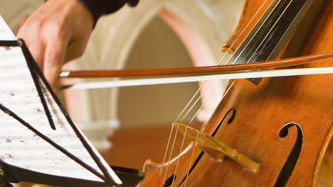 Close-up-of-male-cellist-playing-in-a-string-quartet-in-a-small,-bright-church