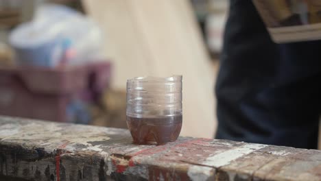 Pouring-Danish-oil-into-a-plastic-cup