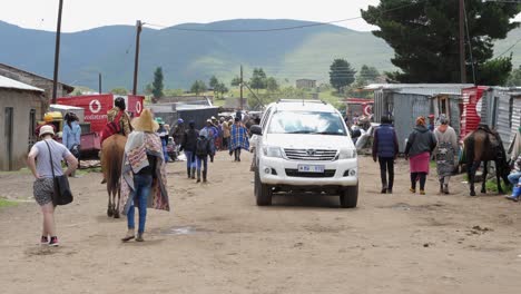 White-pickup-truck-drives-slowly-on-dirt-street-in-Semonkong,-Lesotho