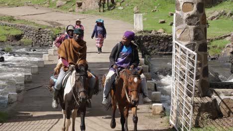 Familia-Africana-En-Lesotho-Cruza-Un-Pequeño-Puente-Sobre-El-Río-A-Caballo