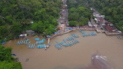 Aerial-view-of-fisherman-boats-anchored-on-the-harbour-with-brown-sea-water