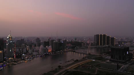 Ho-Chi-Minh-Stadt,-Vietnamesische-Ikonische-Skyline-Und-Saigon-Fluss.-Abendufer-Langschwenkaufnahme-Am-Wasser-Mit-Allen-Wichtigen-Gebäuden,-Die-Vor-Dem-Wunderschönen-Farbigen-Himmel-Beleuchtet-Und-Im-Fluss-Reflektiert-Werden
