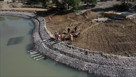 Drone-view-of-construction-workers-moving-earth-to-build-an-artificial-pond