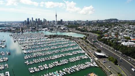 Auckland-cityscape-with-yachts-at-pier-and-highway-to-North,-aerial-view