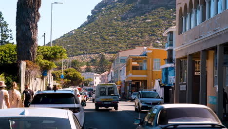 Tourists-and-street-traffic-through-quaint-Kalk-Bay-coastal-town,-Cape-Peninsula