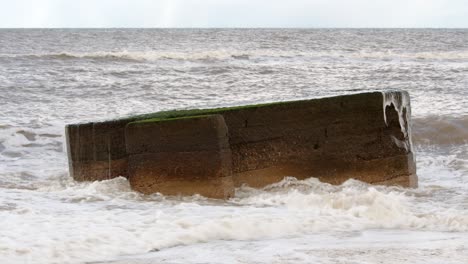 Waves-breaking-over-the-top-of-a-World-War-II-century-pillar-box-on-the-Hemsby-beach