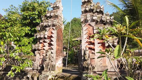 Arquitectura-De-Entrada-De-La-Puerta-Del-Templo-En-Un-Hermoso-Pueblo-Verde-Con-Cielo-Azul-Bali-Indonesia-Plantas-Y-Palmeras-Ondeando,-Ambiente-Religioso-Y-Tranquilo-Sidemen-Karangasem
