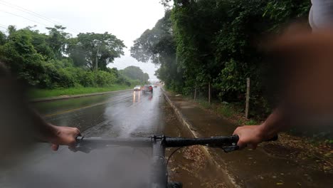 Cyclist-on-a-road-with-rain-and-car-traffic,-first-person-view