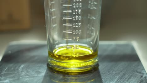Close-up-pouring-sun-flower-oil-in-a-measuring-cup,-shallow-focus