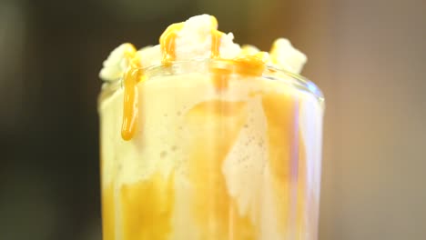 Close-Up-View-Of-Fresh-Made-Milkshake-With-Caramel-Dripping-By-Side-Of-Glass