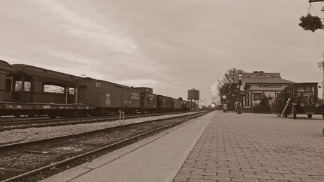 A-Black-and-White,-Sepia-View-of-Antique-Steam-Passenger-Train,-With-a-Low-Camera-Angle,-Arriving-into-a-Train-Station,-Blowing-Smoke-on-a-Winter-Day